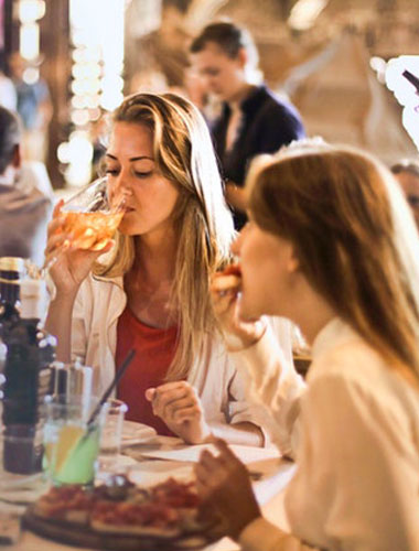 Two women are eating donuts at a restaurant.