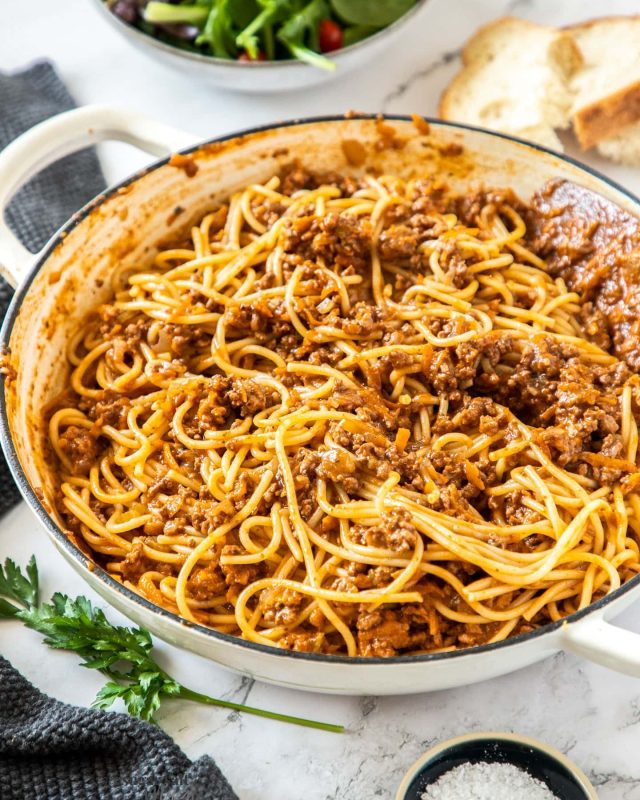 A bowl of spaghetti and meat on top of a table.