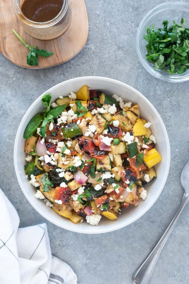 A bowl of salad with feta cheese and vegetables.