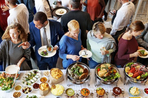 A group of people standing around a table with food.