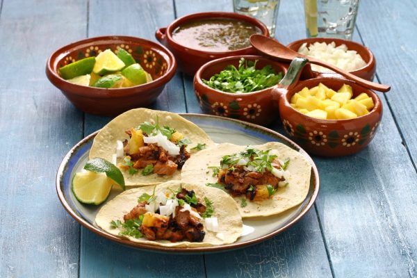 A plate of tacos and bowls of food on the table.