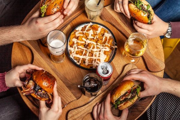 A group of people sitting around a table with hamburgers.