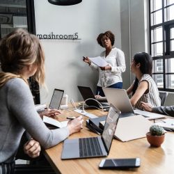 A group of people sitting at a table with laptops.